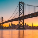 Bay Bridge at sunset, with the San Francisco skyline in the distance