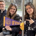 International students on Muni holding an SFSU pennant