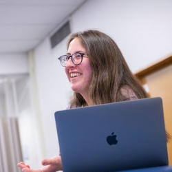 Woman with laptop in class smiling and explaining