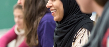 Graduate student in hijab listens and smiles in class
